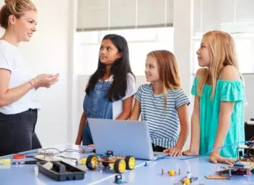 Three female students with female teacher building robots.