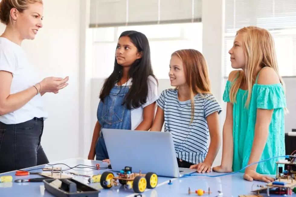 Three female students with female teacher building robots.